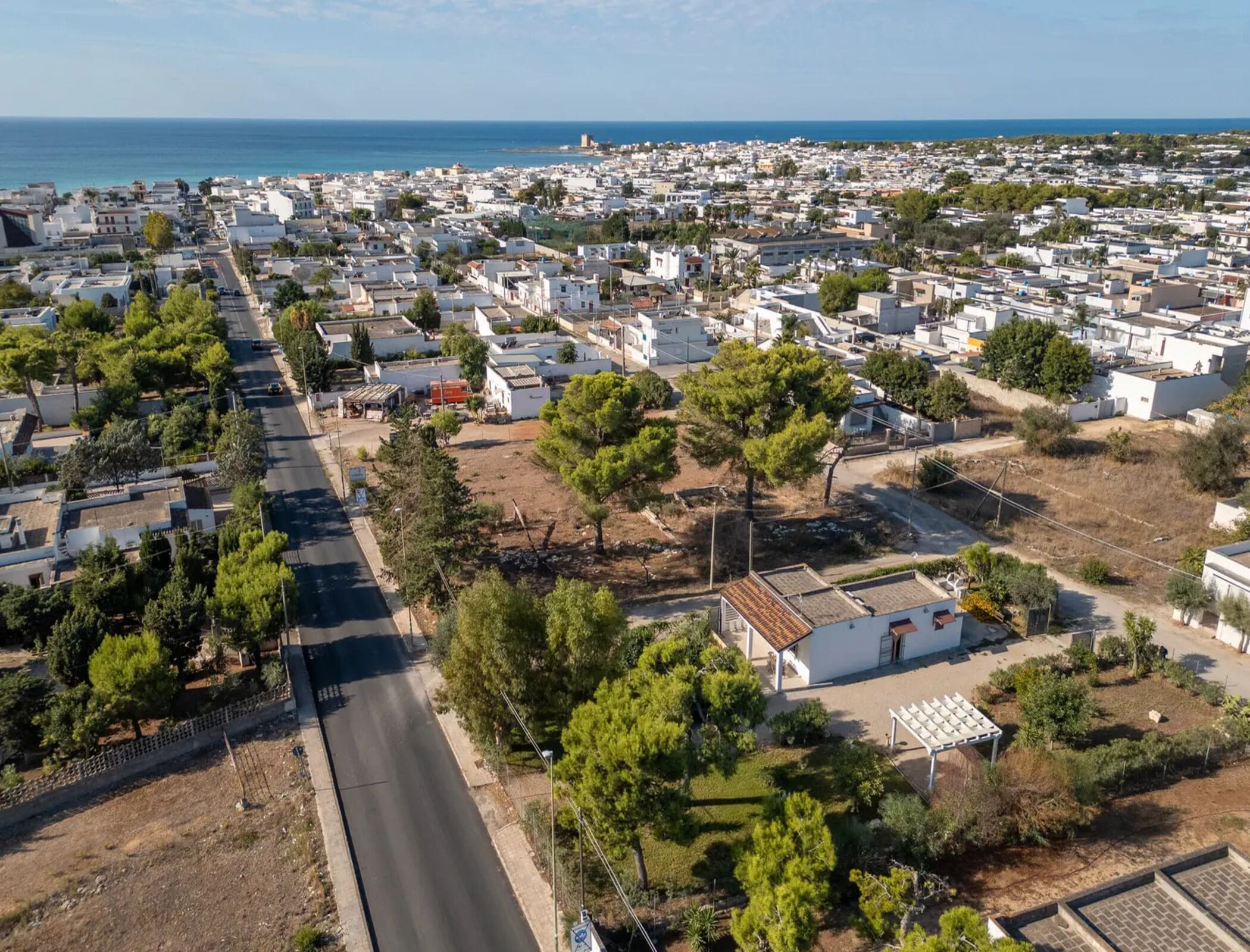Zona residencial con una calle principal, casas y vistas al mar.