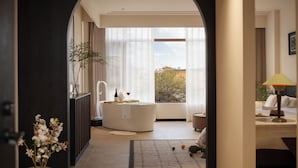 Uma casa de banho moderna com banheira, chuveiro e uma janela grande com cortinas.