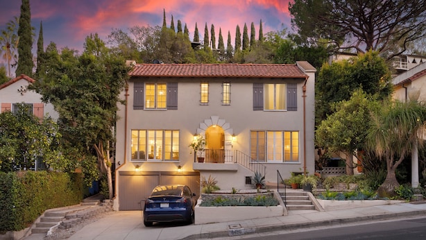 A two-story house with a garage, a car parked in front, and a well-maintained garden.