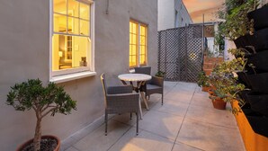 A patio with a table and chairs, a potted tree, and a building with windows.