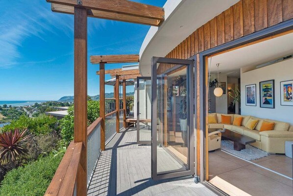 Een modern balkon met glazen deuren die uitkomen op een woonruimte met een bank en kunstwerken.