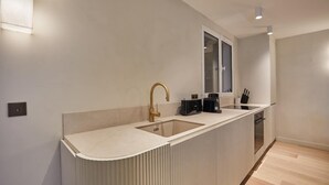 Une cuisine moderne dotée d’un plan de travail incurvé, d’un robinet doré et d’une fenêtre située au-dessus de l’évier.