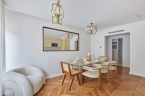 A dining area with a glass table, wooden chairs, and a modern chandelier. - Two-bedroom flat in central Paris (Paris)