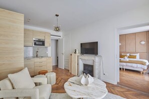 A modern hotel room with a kitchen, a fireplace, a TV, and a bed. - Two-bedroom flat in central Paris (Paris)