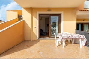 A balcony with a table and chairs, a sliding glass door, and a tiled floor.