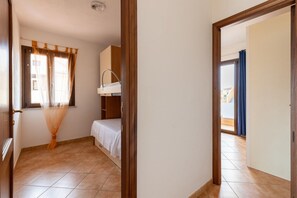 A room with a bed, a window with curtains, a sink, and a view of the outside.