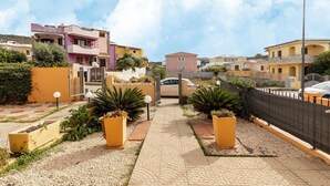 Un quartier résidentiel doté d’un chemin piétonnier dallé, de jardinières jaunes et de maisons aux couleurs pastel.