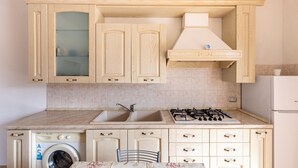 Une cuisine avec des meubles de rangement en bois, un lave-linge, une cuisinière à gaz et un réfrigérateur.