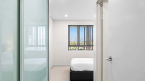 A bedroom with a bed, a window with blinds, and a door. - Seaside Retreat with Parking and Balcony (Newport)