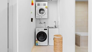A compact laundry room with a washing machine, dryer, and sink. - Seaside Retreat with Parking and Balcony (Newport)
