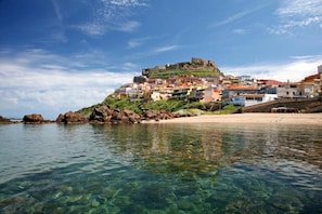 A coastal town with clear waters, a sandy beach, and buildings on a hill. - Apartment with air conditioning and sea views (Castelsardo)