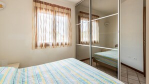 A bedroom with a large bed, a mirror, and a sliding door closet. - Apt con giardino, a 300-metre-tall mare (Lu Bagnu)