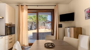 A modern kitchen with a built-in oven and a dining area with a wooden table and white chairs. - Air-conditioned with garden and private parking (Badesi)