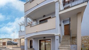 A multi-story residential building with balconies, a staircase, and a gated entrance. - Air-conditioned with garden and private parking (Badesi)