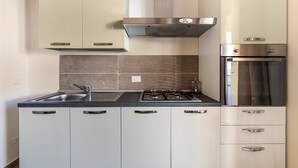 A modern kitchen with a gas stove, sink, and built-in oven. - Air-conditioned with garden and private parking (Badesi)