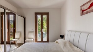A bedroom with a bed, a chair, and a sliding door leading to a balcony. - Air-conditioned with garden and private parking (Badesi)