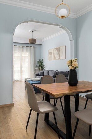 Un comedor con una mesa y sillas de madera, un sofá y un jarrón con flores.