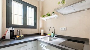 Een moderne keuken met een ingebouwde oven, een spoelbak en een raam met zonwering.