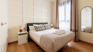 Een hotelkamer met een bed, nachtkastje, lamp en een spiegel aan de muur.