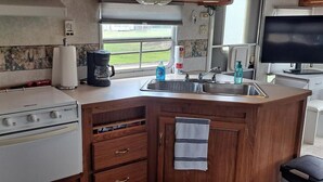 A compact kitchen with a stove, coffee maker, and sink. - Comfortable RV in rural area - West Richland (West Richland)