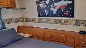 A bedroom with a bed, a dresser, a map on the wall, and a clock. - Comfortable RV in rural area - West Richland (West Richland)