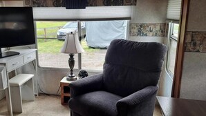 A compact living space with a television, a desk, a chair, and a lamp. - Comfortable RV in rural area - West Richland (West Richland)