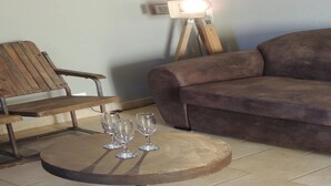 A living room with a brown sofa, wooden bench, and a round table with three glasses.