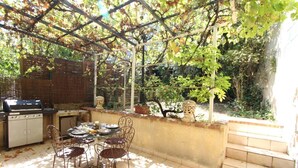 An outdoor patio with a grill, table, and chairs.