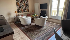 Una sala de estar con un sofá, dos sillones, una mesa de centro, un televisor y un ventanal grande.