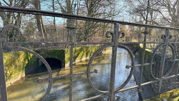 Un puente metálico con la entrada de un túnel sobre un río.