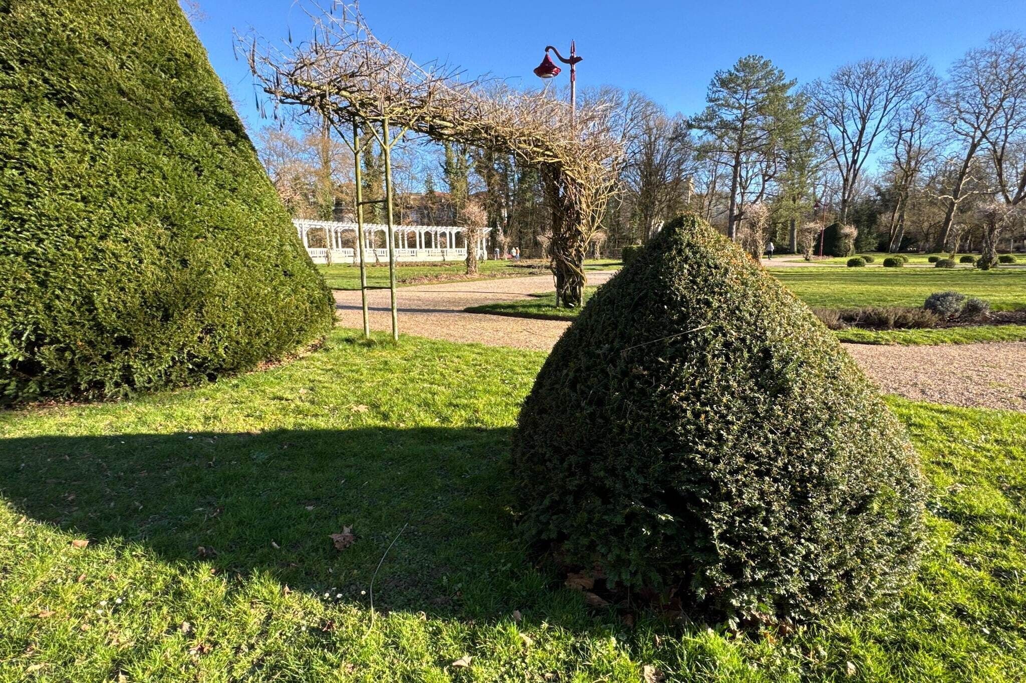 A well-maintained garden with neatly trimmed hedges, a gazebo, and a clear sky.