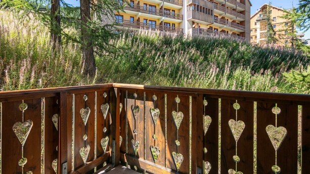 A multi-story hotel with balconies, surrounded by dense greenery and trees. - Two-Room Alpine Base for 5 (Risoul)