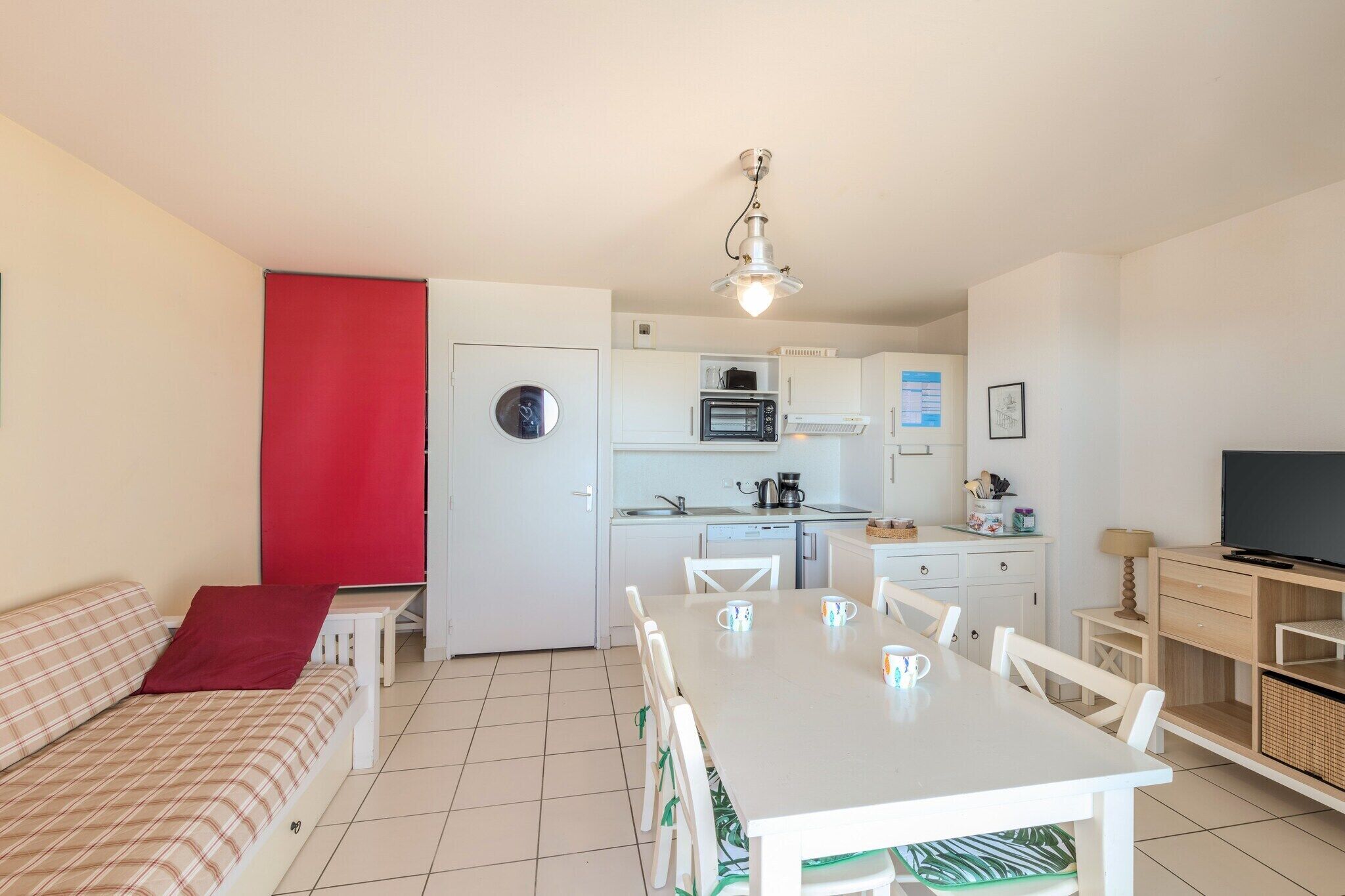 Een ruimtelijke woonkamer met een kitchenette, een eethoek en een zithoek.