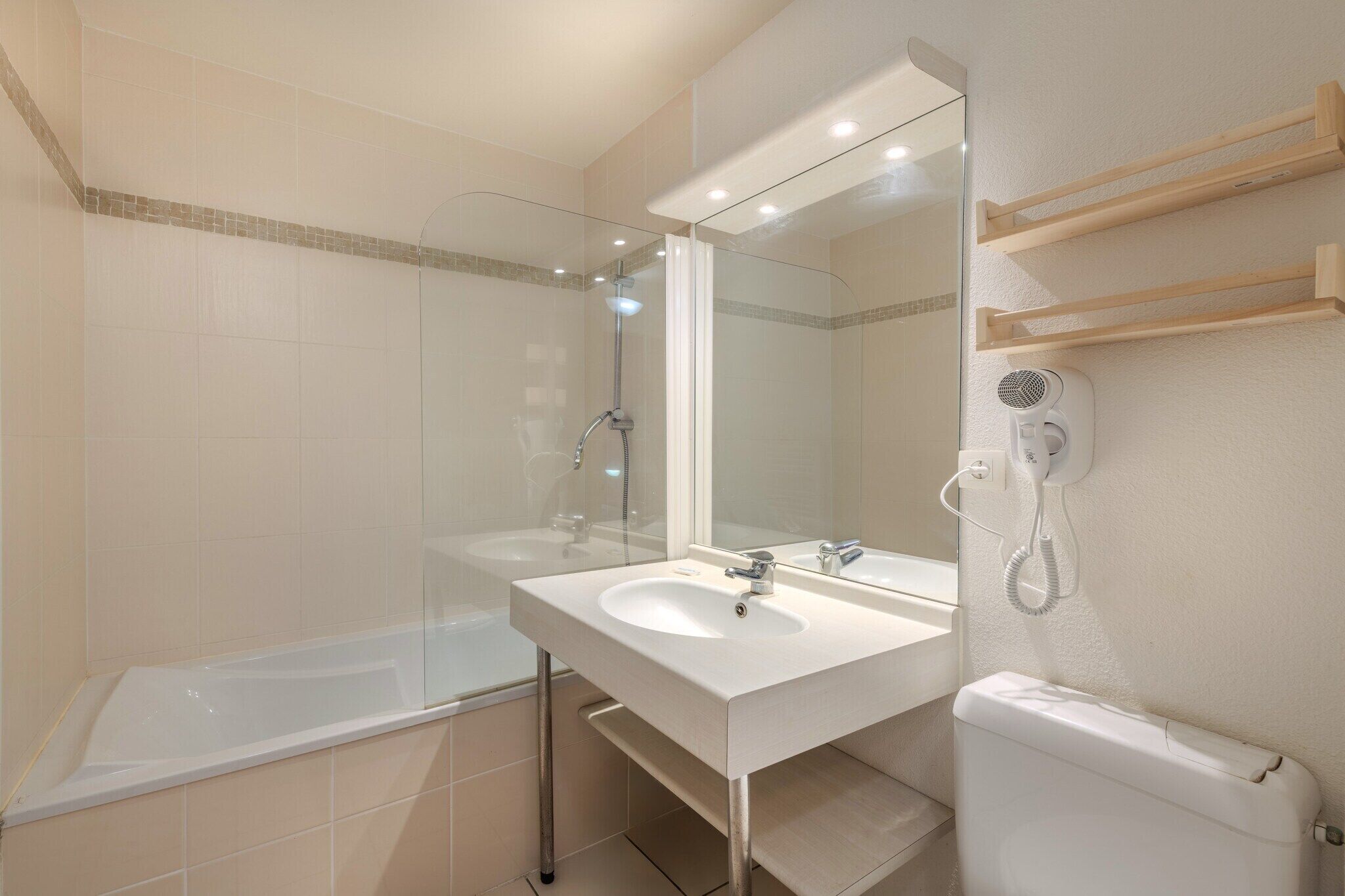 Un baño moderno con ducha de vidrio, un lavamanos blanco y un inodoro.