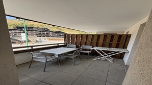 A balcony with a table and chairs, a view of buildings, and a wooden fence. - 3-bedroom apartment for six guests (Les 2 Alpes)