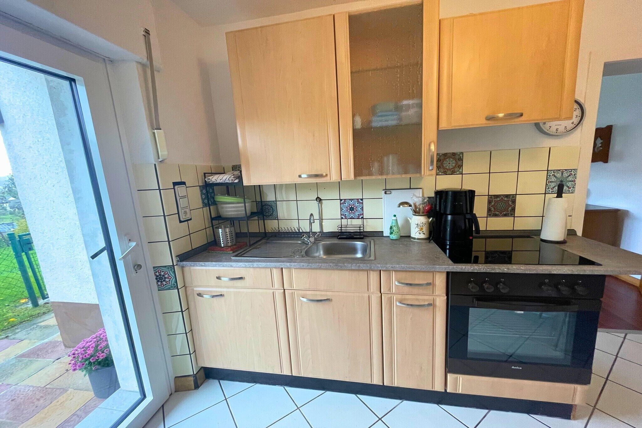 Una cocina con armarios de madera, un lavamanos, una estufa y una ventana.