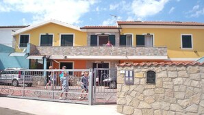 Un bâtiment à deux étages, doté d’une façade en pierre, d’une entrée fermée par un portail et d’un balcon bien visible.