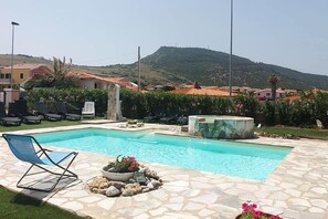 A swimming pool with lounge chairs, a hot tub, and a mountainous backdrop. - 150 meters from the sea, 2 swimming pools (Valledoria)
