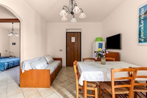 Ein Zimmer mit einer Holzdavonia, einem Esstisch mit Stühlen, einem Fernseher und einer Tür mit einem Schild.