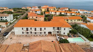 Ein Küstenwohngebiet mit Häusern mit Terrakotta-Dächern, einem Swimmingpool und Blick aufs Meer.