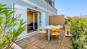 Eine Terrasse mit Tisch und Stühlen, ein Holzzaun und ein Gebäude mit einer Schiebetür.