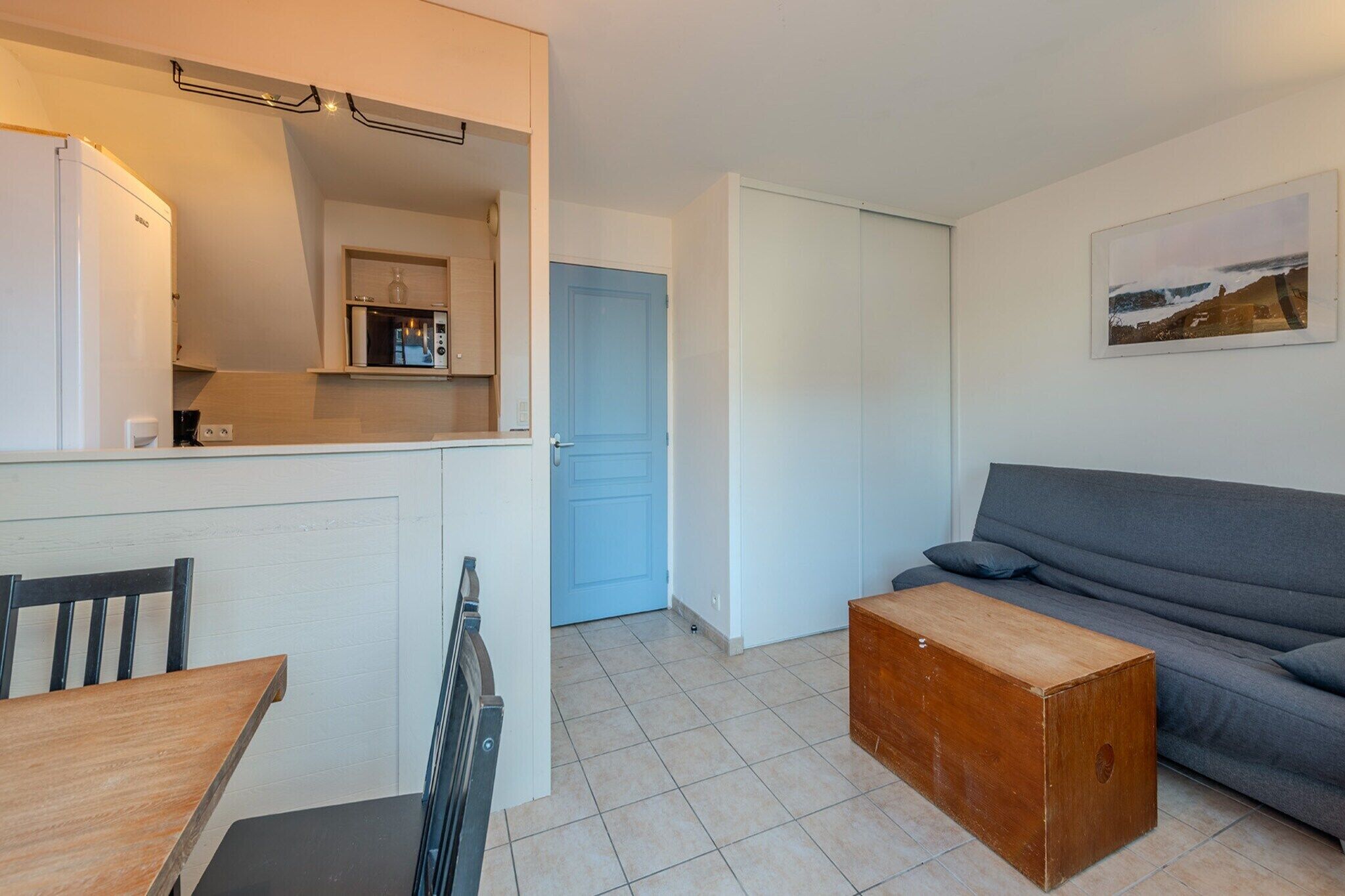A compact living space with a kitchenette, a dining area, a sofa, and a small wooden table.