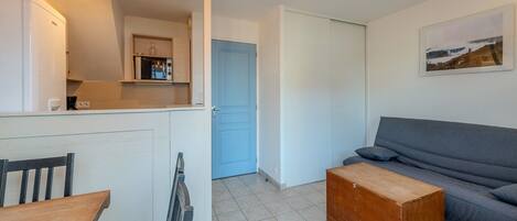 A compact living space with a kitchenette, a dining area, a sofa, and a small wooden table.