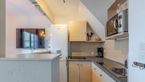 Une cuisine compacte équipée d’un réfrigérateur intégré, d’un four à micro-ondes et d’un évier.