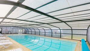 Une piscine intérieure avec des couloirs de nage bien délimités, une structure de toit et des chaises longues disposées le long des bords.