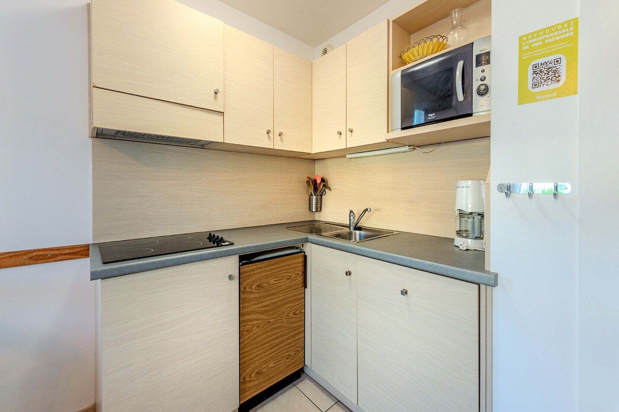 A compact kitchenette with a microwave, sink, and a coffee maker.
