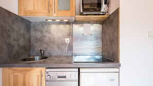 A compact kitchen with a built-in microwave, dishwasher, and a stainless steel refrigerator.