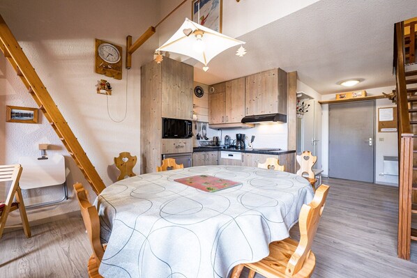A cozy kitchen with wooden cabinets, a microwave, and a dining area with a table and chairs.