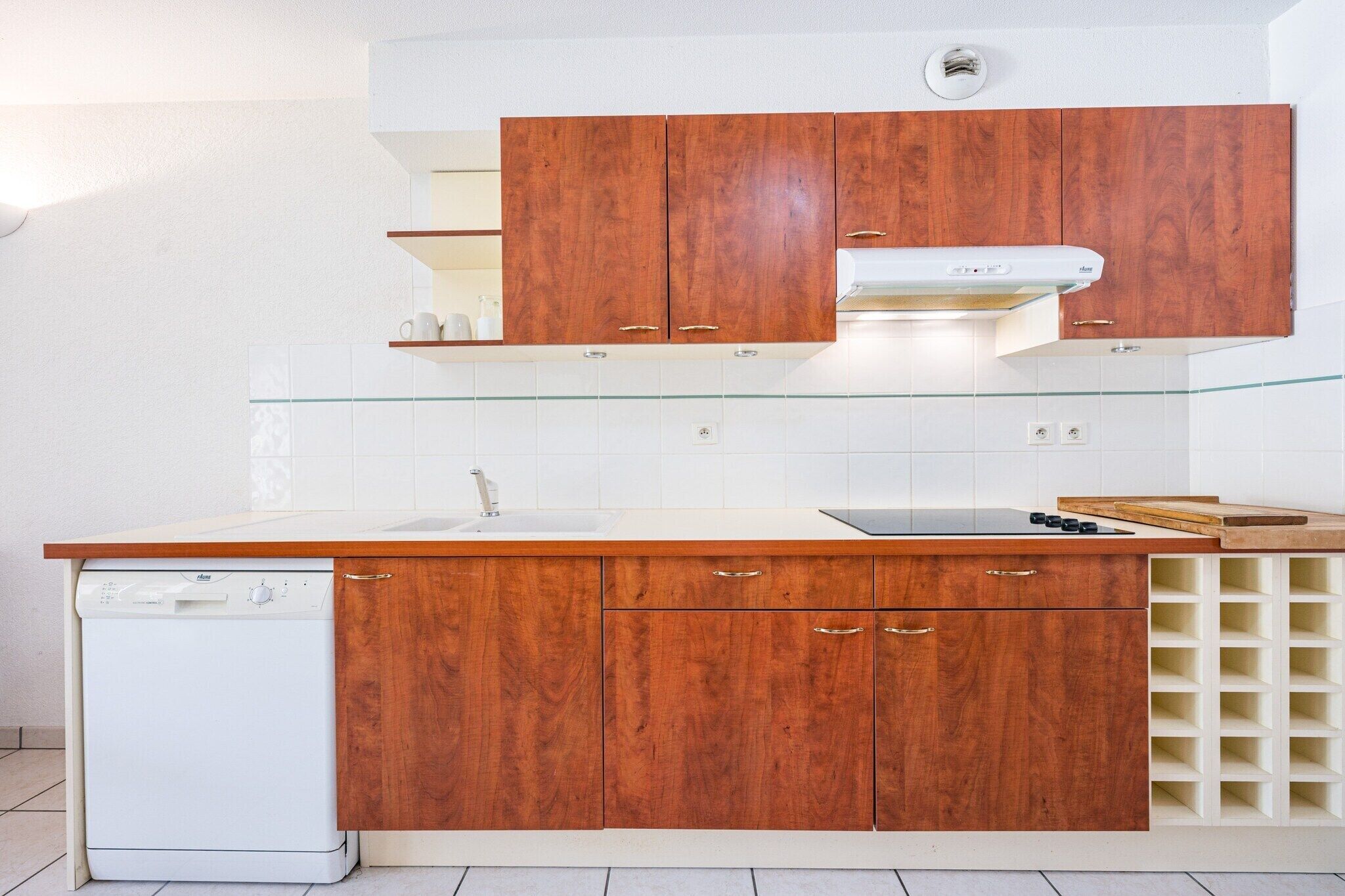 A kitchen with wooden cabinets, a dishwasher, a white countertop, and a built-in wine rack.