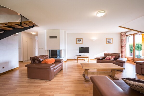 Ein modernes Wohnzimmer mit Treppe, Holzböden und einem Flachbildfernseher.